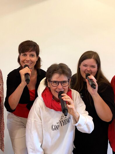 Gesangsgruppe Herzonanz mit Mikrofonen in lebendiger Performance – gemeinsame Stimme und musikalische Leidenschaft beim Curkonzert in Bad Gleichenberg. | © Herzonanz