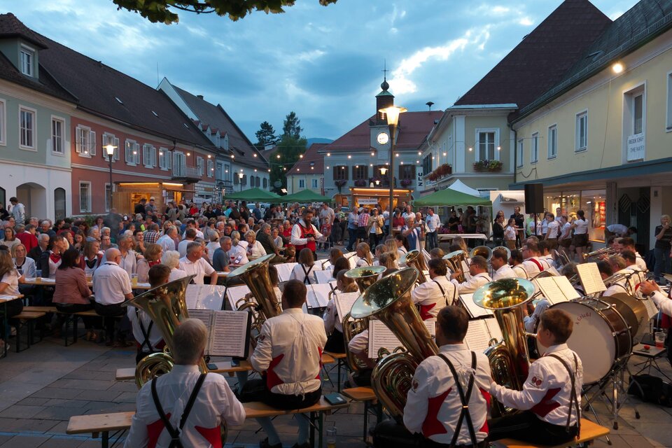 Ein lebhaftes Straßenfest mit vielen Menschen und einer Blaskapelle im Vordergrund. Die Atmosphäre ist festlich und fröhlich. | © Martin Scherer