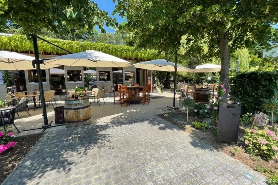 Ein einladendes Café im Freien mit Sonnenschirmen und Tischen. Die Umgebung ist grün und blühend, ideal für entspannte Momente. | © Weinkastl