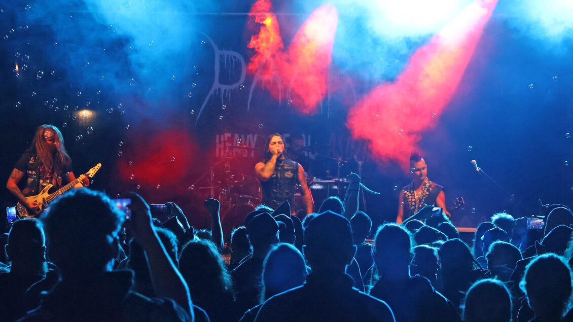 Eine Live-Band spielt vor einem begeisterten Publikum. Die Bühne ist mit buntem Licht und Nebel beleuchtet. | © Stadt Bruck
