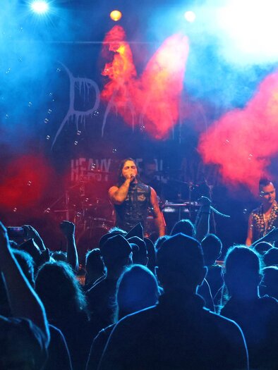 Eine Live-Band spielt vor einem begeisterten Publikum. Die Bühne ist mit buntem Licht und Nebel beleuchtet. | © Stadt Bruck