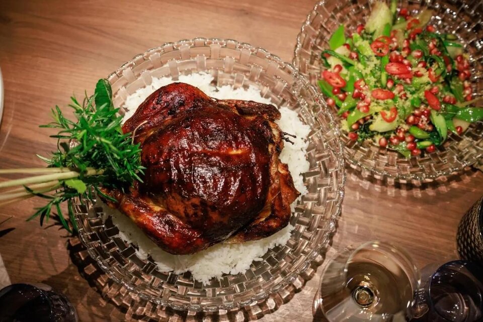 Ein gebratener Hühnchen auf einem Bett aus Reis, garniert mit frischen Kräutern. Daneben befindet sich ein bunter Salat mit Tomaten und Gurken. | © Martina Schmit