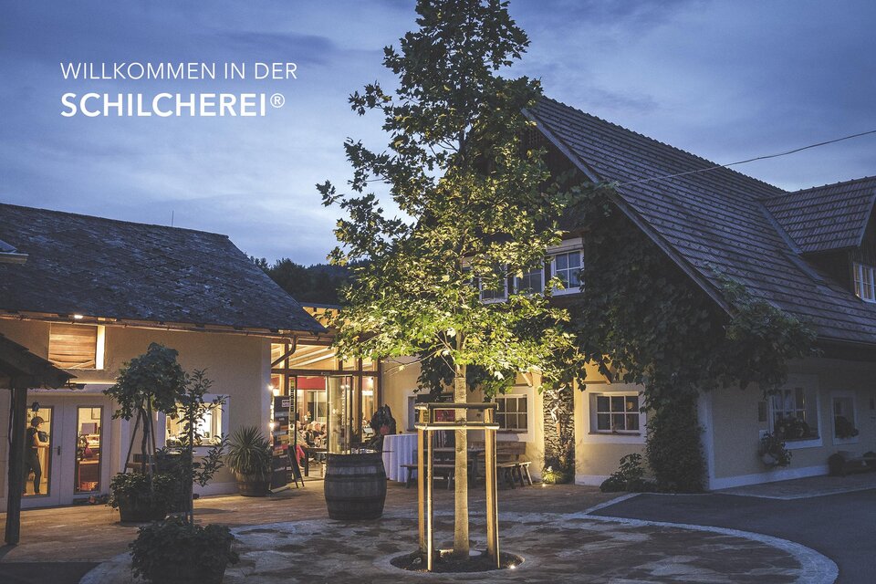 Ein einladendes Restaurant mit einem charmanten, hell erleuchteten Eingang. Zeitgemäße Architektur umgeben von grünem Baum und Garten. | © @Florian Jöbstl
