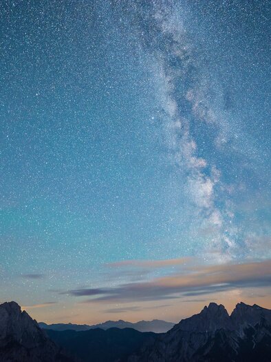 Ein klarer Nachthimmel mit vielen Sternen und der Milchstraße, die sich deutlich abhebt. Im Vordergrund sind bergige Silhouetten zu sehen. | © Nationalpark Gesäuse