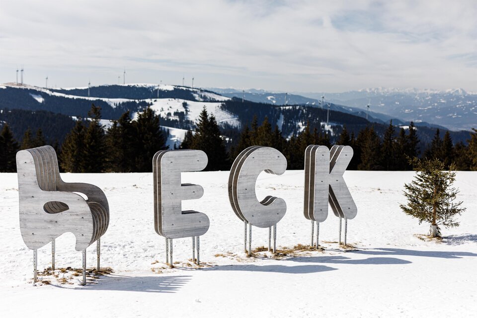 Eine Schneelandschaft mit großen, stilisierten Buchstaben, die das Wort „BECK“ bilden. Im Hintergrund sind verschneite Berge und ein klarer Himmel zu sehen. | © TV Hochsteiermark, nicoleseiser.at