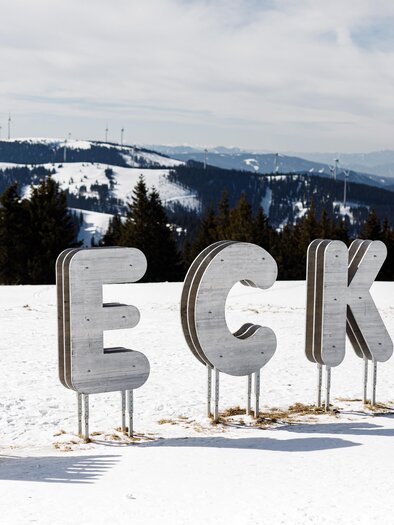 Eine Schneelandschaft mit großen, stilisierten Buchstaben, die das Wort „BECK“ bilden. Im Hintergrund sind verschneite Berge und ein klarer Himmel zu sehen. | © TV Hochsteiermark, nicoleseiser.at
