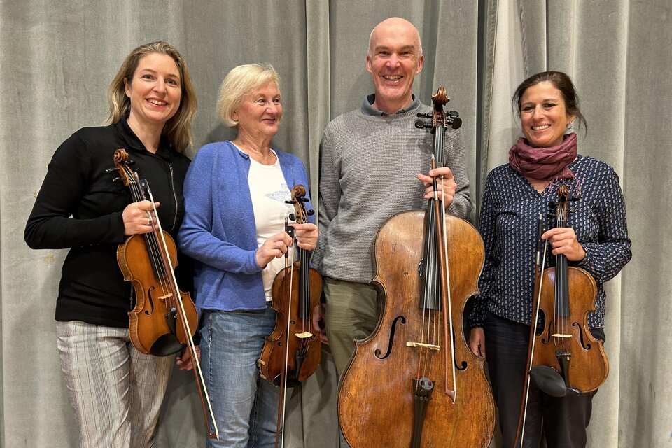 Vier Musiker:innen halten ihre Instrumente und lächeln in die Kamera. Im Hintergrund ist ein grauer Vorhang sichtbar. | © Verein auf der Pürgg