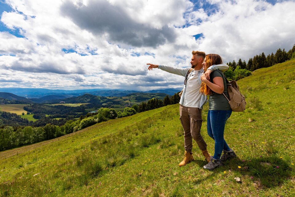 Wanderweg führt über eine Wiese, die Wanderer genießen die herrliche Aussicht. | © Region Graz-Harry Schiffer