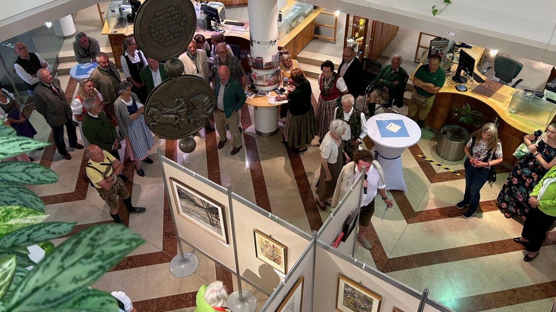 Bei der Vernissage malerisches Aussseerland im Gebäude der Vollkbank in Bad Aussee sind die ausgestellten Kunstwerke zu sehen, welche von einigen Besuchern bewundert werden.  | © Volksbank Bad Ausee