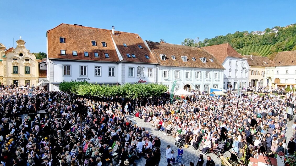 Eine große Menschenmenge versammelt sich auf einem Platz vor historischen Gebäuden. Der sonnige Himmel und die Feierlichkeiten schaffen eine festliche Atmosphäre. | © Oststeiermark Tourismus