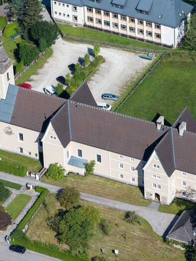 Eine schlichte Kirche mit einem befestigten Gelände und einem kleinen Garten. Im Hintergrund sind mehrere Gebäude und Autos zu sehen. | © Dioezese Graz-Seckau