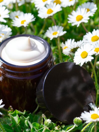 Open glass with white cream among daisies in a meadow in Graz, next to it is the lid. | © Evelyne Sausen-Julia Sauseng