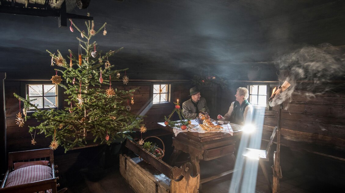 Ein gemütlicher, rustikaler Raum mit einem schön geschmückten Weihnachtsbaum. Zwei Personen sitzen an einem Tisch und genießen eine festliche Mahlzeit. | © ÖFM-Johannes Kernmayer