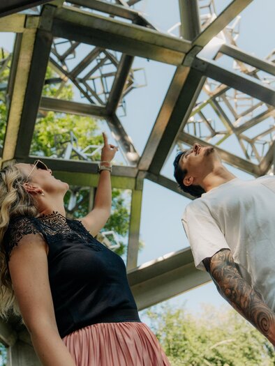 Zwei Personen betrachten Kunstinstallationen im Skulpturenpark Premstätten unter freiem Himmel. | © studio draussen