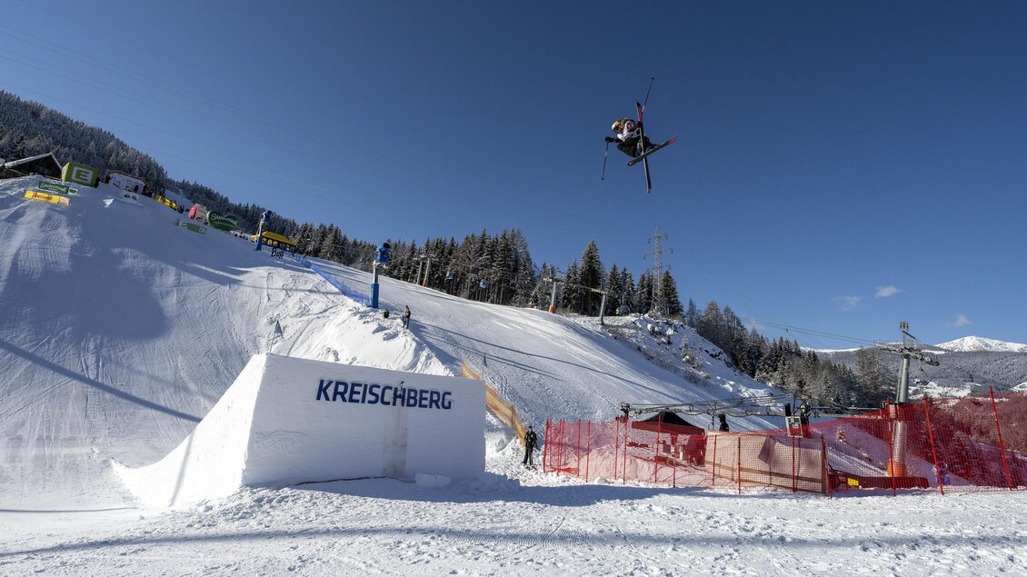 Ein Skifahrer springt über einen Sprung im Schnee. Im Hintergrund sind Bäume und ein blauer Himmel zu sehen. | © TVB Murau