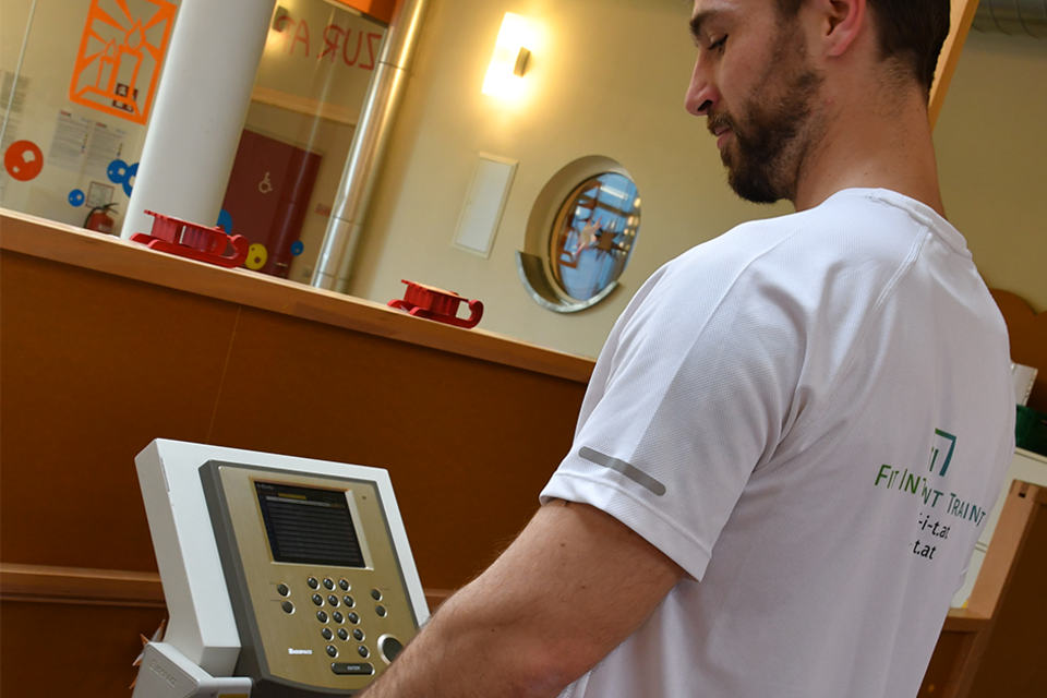 Ein Mann testet ein Fitnessgerät in einem modernen Trainingsraum. Im Hintergrund sind verschiedene Geräte und symbolische Fitness-Elemente sichtbar. | © H2O-Hoteltherme GmbH / FIT