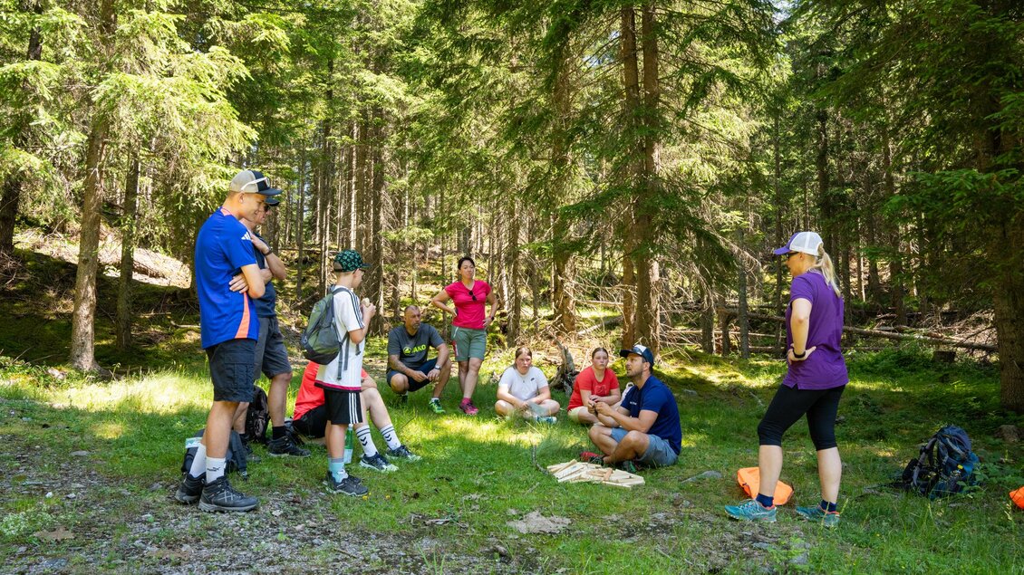 Eine Gruppe von Menschen versammelt sich in einem Wald. Sie hören einem Vortrag zu und genießen die natürliche Umgebung. | © TVB/Laura Passenbrunner