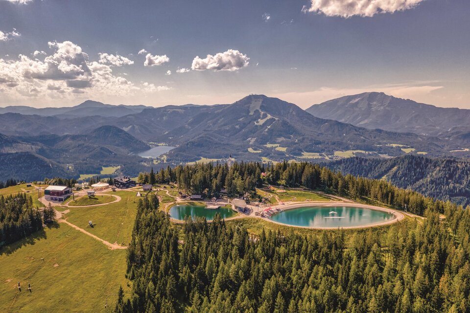 Eine malerische Landschaft mit Bergen und einem klaren blauen See. Umgeben von dichtem Wald und sanften Hügeln. | © Rudy Dellinger