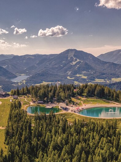 Eine malerische Landschaft mit Bergen und einem klaren blauen See. Umgeben von dichtem Wald und sanften Hügeln. | © Rudy Dellinger