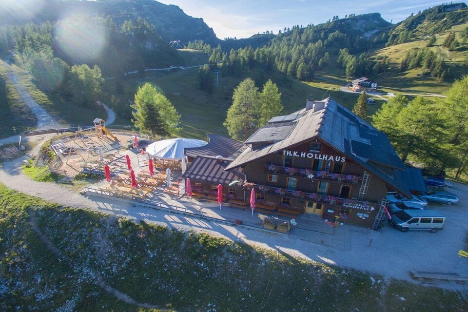 <p>Ein gemütliches Berggasthof Hollhaus umgeben von grünen Bergwiesen und Bergen. Im Hintergrund ist die Tauplitzalm und ein klarer blaue Himmel zu sehen.</p> | © Berggasthof Hollhaus