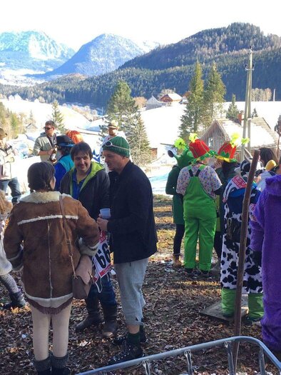 A lively crowd in colorful costumes at the "Fassdaubenrennen" barrel racing event in the wintry mountain landscape of Lupitsch in the Ausseerland region. In the background, snow-covered meadows and mountains can be seen. | ©  Christiane Pressl