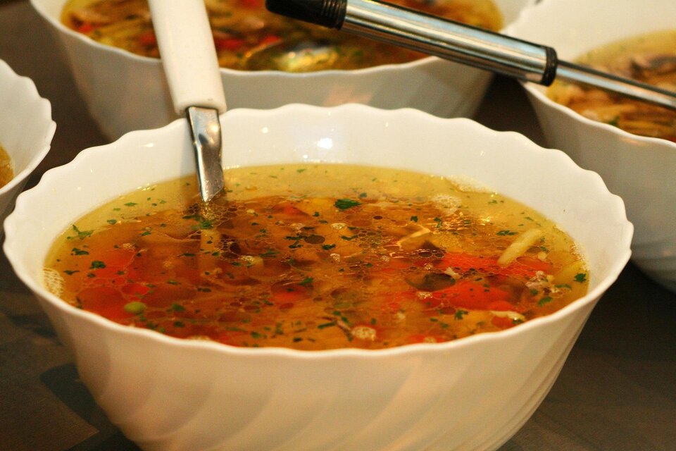Eine Schüssel mit brühender Suppe, gefüllt mit Gemüse und Kräutern. Im Hintergrund sind mehrere ähnliche Schüsseln zu sehen. | © Pixabay