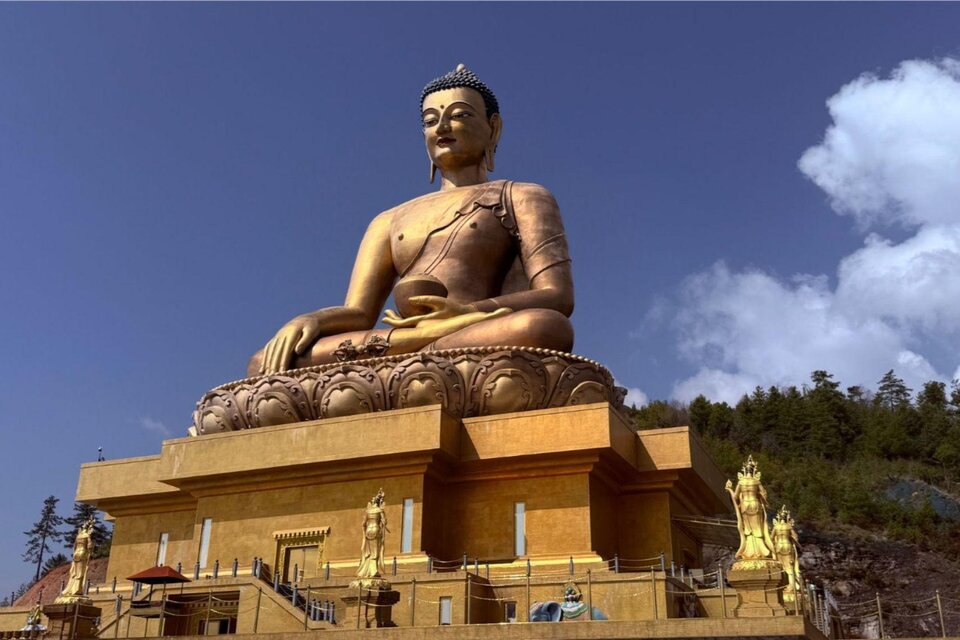 <p>Eine riesige Buddha Statue in Gold. Im Hintergrund sind beeindruckende Felsformationen und blauer Himmel zu sehen.</p> | © Helmut Pichler, www.gosauer.at