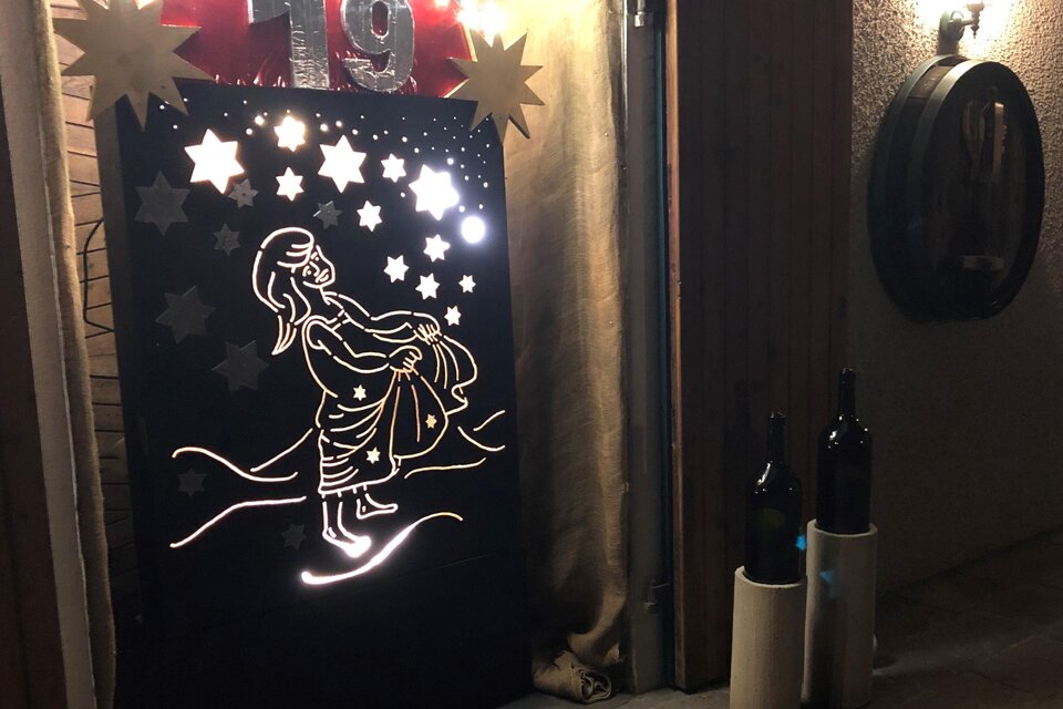 Stimmungsvoll beleuchtetes Adventfenster beim Weinhof Gwaltl, Sternenmotiven und einer weihnachtlichen Darstellung.
 | © Weinhof Gwaltl