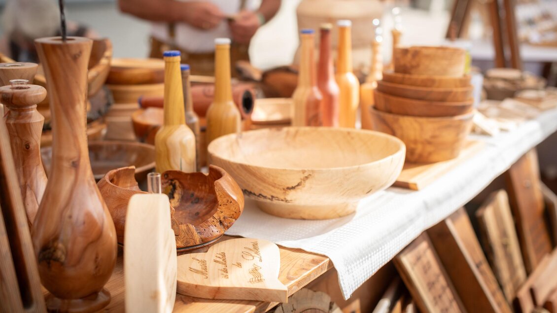 Ein Marktstand mit handgefertigtem Holzgeschirr und Dekorationsgegenständen. Die Objekte sind in verschiedenen Größen und Formen angeordnet. | © Stefanie Dornik Photography