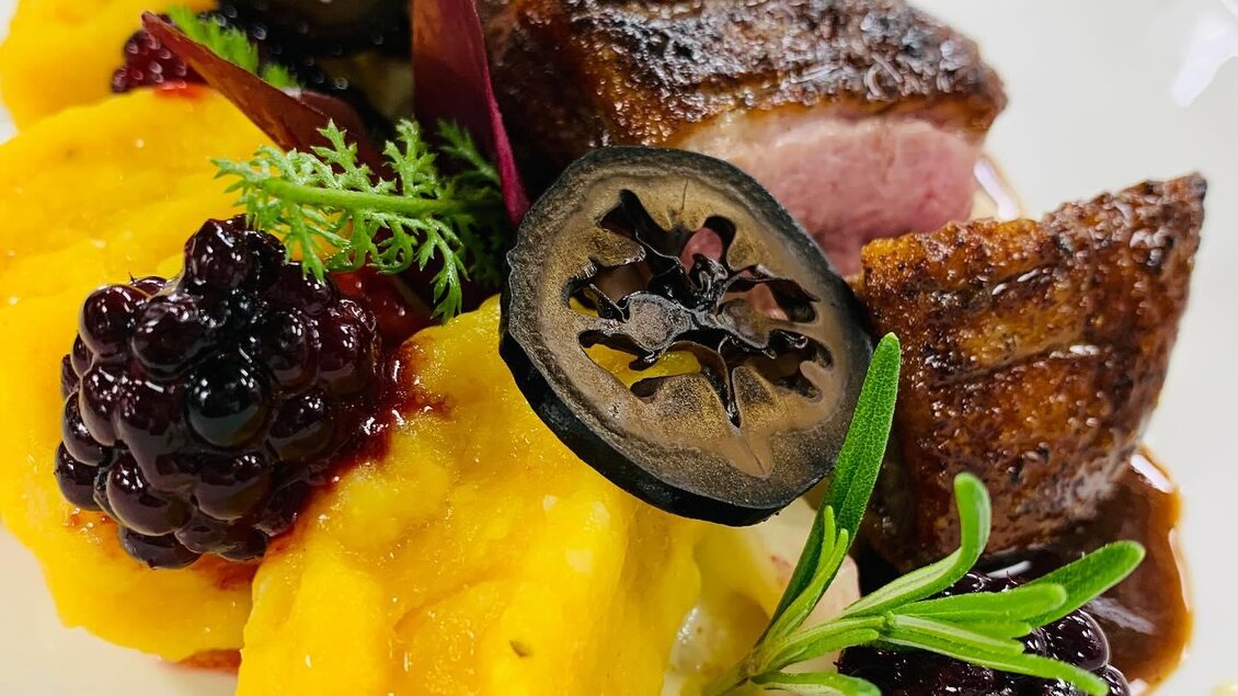 Ein kunstvoll angerichteter Teller mit gegrilltem Fleisch, pürierten Gemüsen und frischen Beeren. Die Präsentation ist farbenfroh und ansprechend. | © Petra Meißl