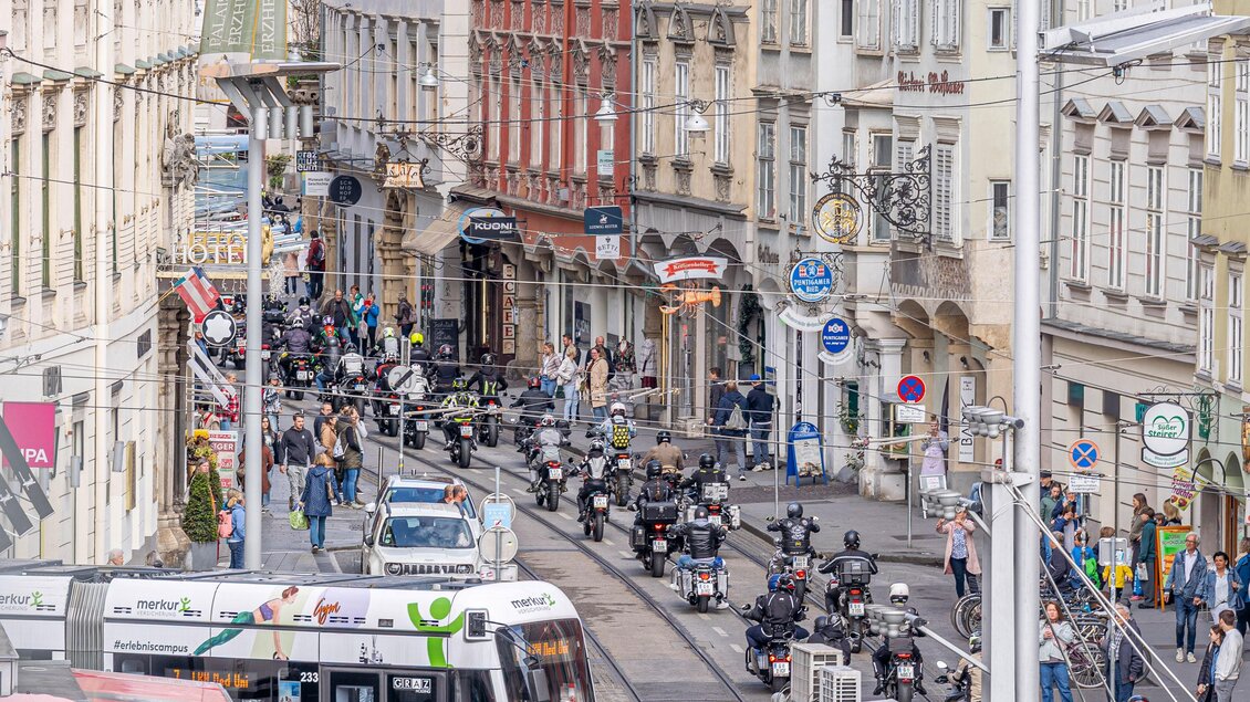 Motorradkorso bei Benefizfahrt am Grazer Hauptplatz, Menschen entlang der Straße und Straßenbahn im Stadtzentrum. | © Fellows Ride