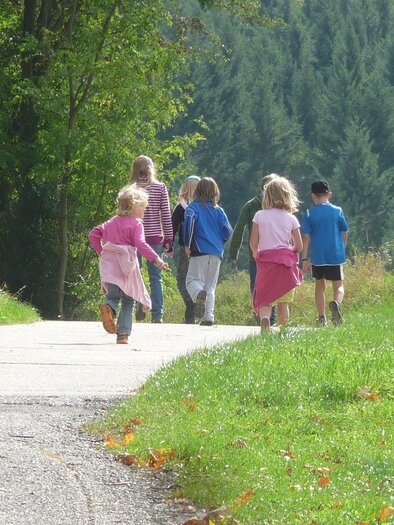 A group of children is walking along a path through nature. Surrounded by trees and green grass, they are having fun on the outing. | © Pixabay