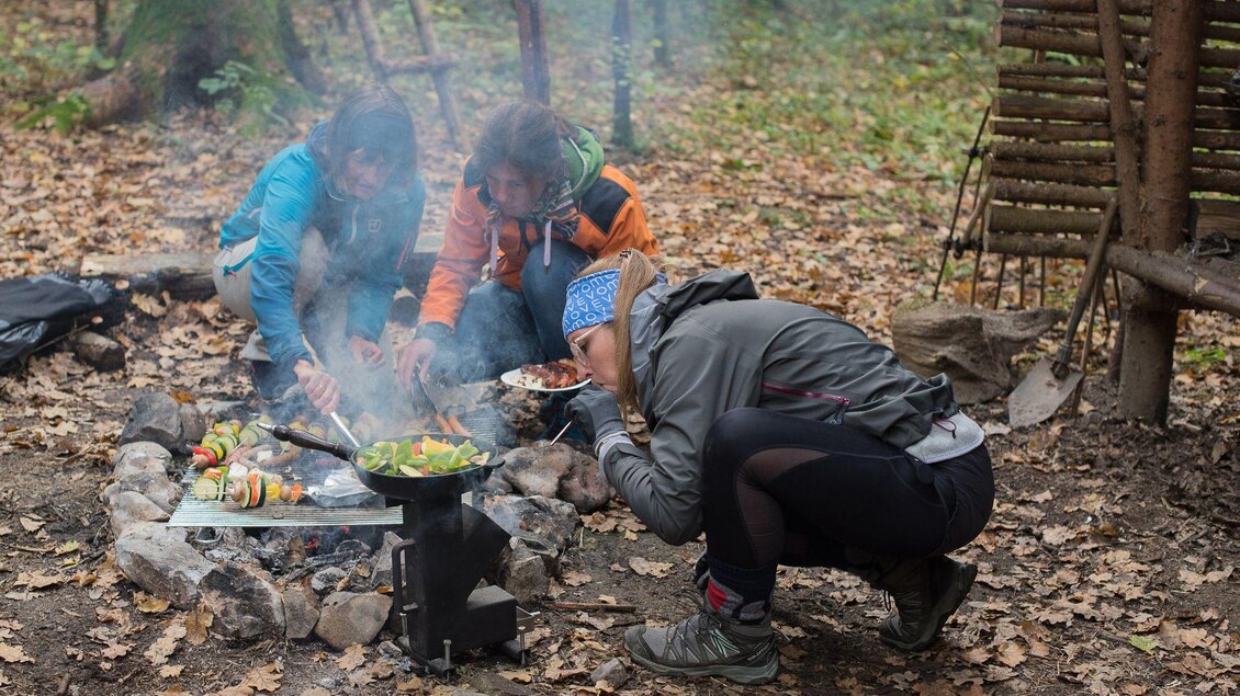 Drei Erwachsene kochen über Lagerfeuer im Wald bei der Hirzmannsperre in Edelschrott, mit Grill und Pfanne. | © Julia C. Pirkenau