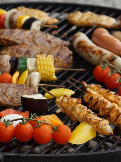 Ein Grill mit verschiedenen Fleischsorten, Würstchen und buntem Gemüse. Die Speisen sind frisch zubereitet und appetitlich angeordnet. | © Pixabay