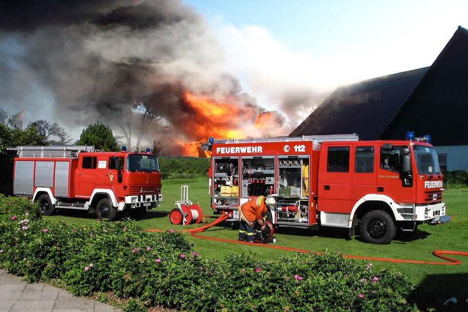 Zwei Feuerwehrfahrzeuge stehen vor einem brennenden Gebäude. Rauch und Flammen steigen in den Himmel. | © pixabay