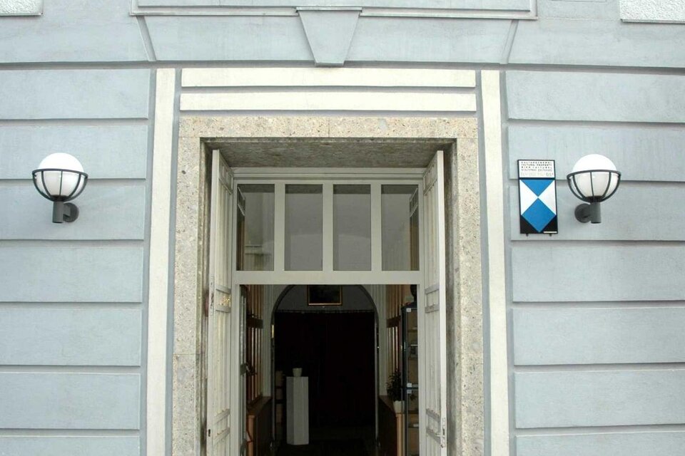 Eingang zum Stadtmuseum mit einem klaren Schild über der Tür. Die Fassade ist hellgrau und hat klassische Lampe an den Seiten. | © Stadtgemeinde Judenburg