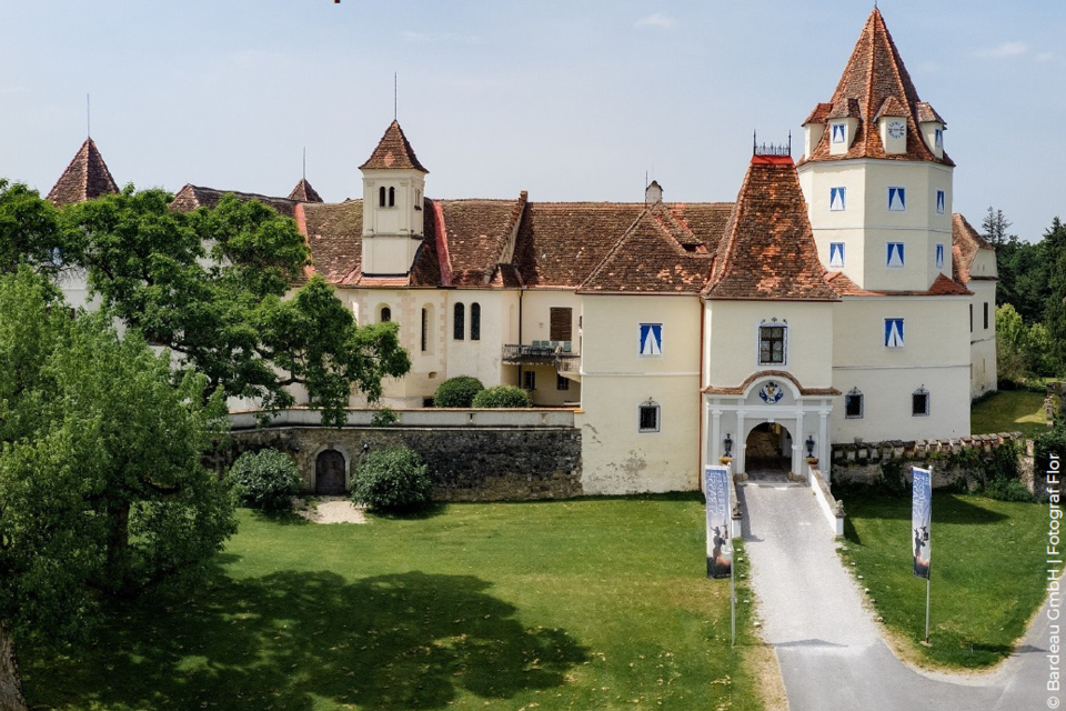 <p>Das  beeindruckende Schloss Kornberg mit roten Dächern und großen Fenstern. Die Umgebung ist grün und einladend, ideal für einen Spaziergang.</p> | © Bardeau GmbH