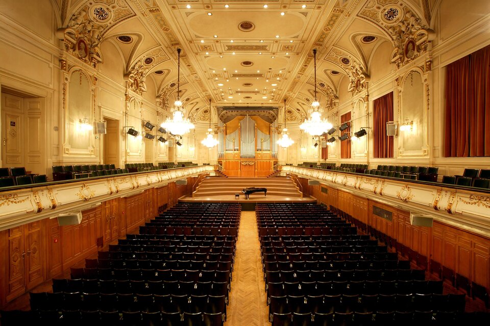 Ein eleganter Konzertsaal mit vielen Sitzplätzen und einer großen Orgel im Hintergrund. Die Decke ist mit beeindruckenden Beleuchtungskörpern und dekorativen Elementen gestaltet. | © Ilemann