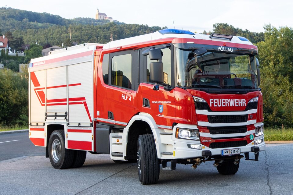 Ein rotes Feuerwehrfahrzeug mit blaulicht. Es steht auf einer Straße vor einer grünen Landschaft. | © FF Pöllau