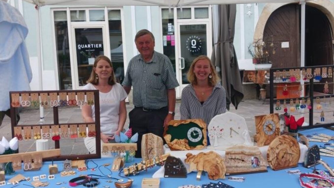 Ein Marktstand mit drei Personen, die Handwerkskunst und Schmuck präsentieren. Es gibt viele verschiedene Gegenstände auf dem Tisch, die zum Kauf angeboten werden. | © Oststeiermark Tourismus