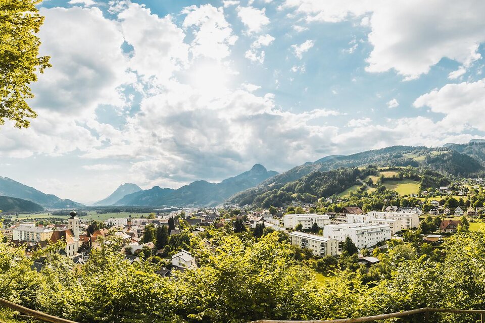 Eine malerische Stadtlandschaft mit Blick auf Berge und grünen Hügeln. Der Himmel ist teilweise bewölkt und die Atmosphäre ist friedlich. | © Thomas Sattler