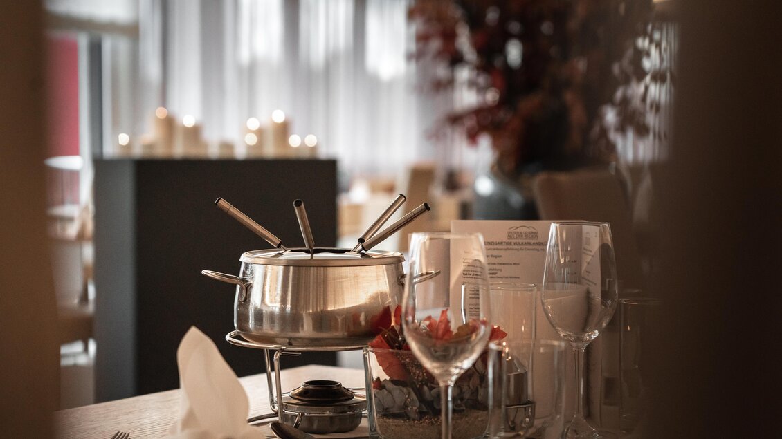 Stilvoll gedeckter Tisch mit Fondue im Vulkanlandhotel Legenstein. Warmes Licht, Kerzenschein und herbstliche Dekoration schaffen eine gemütliche Atmosphäre für genussvolle Stunden. | © Vulkanlandhotel Legenstein