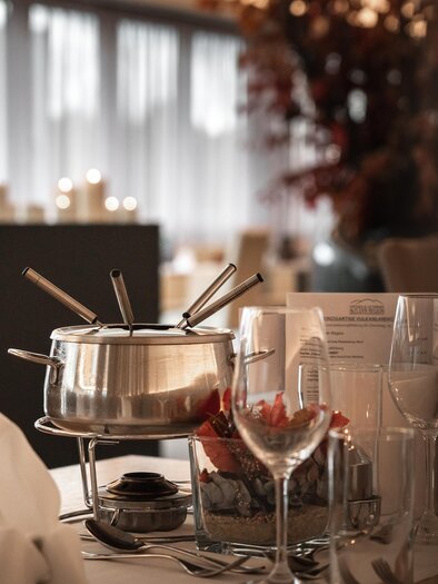 Stylishly set table with fondue at the Vulkanlandhotel Legenstein. Warm light, candlelight, and autumn decoration create a cozy atmosphere for enjoyable moments. | © Vulkanlandhotel Legenstein