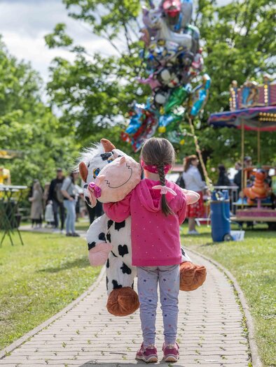 Child with large plush cow on the way to the carousel at the Food & Fun Festival in Premstätten, Styria. | © Foto Fuchs