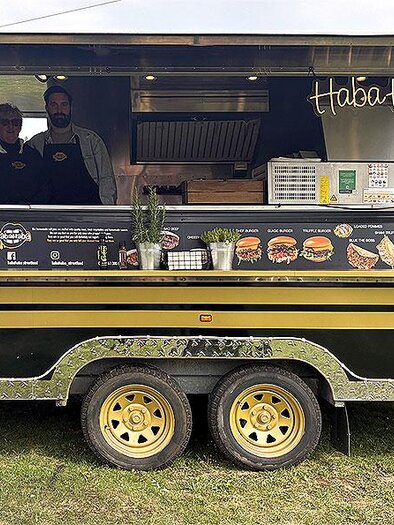 Schwarzer Foodtruck mit geöffnetem Verkaufstresen und zwei Personen beim Food & Fun Festival in Hart bei Graz. | © Foodandfunfestival.at