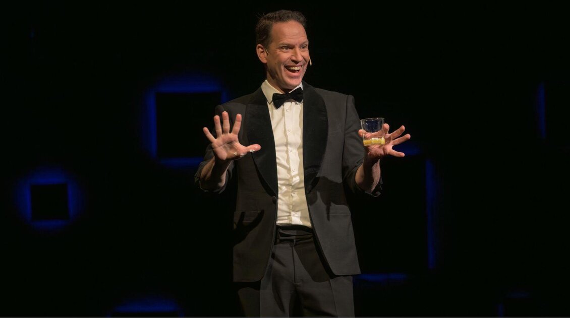 Auf dem Bild ist der Zauberkünstler Alexander Krist während einer seiner Magie & Illusionen Shows zu sehen. Er trägt einen Anzug mit schwarzer Fliege und begeistert das Publikum. | © Alexander Krist