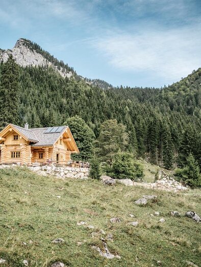 Ein charmantes Holzhaus inmitten von Bergen und Wäldern. Die Szene strahlt Ruhe und Naturverbundenheit aus. | © Stefan Leitner