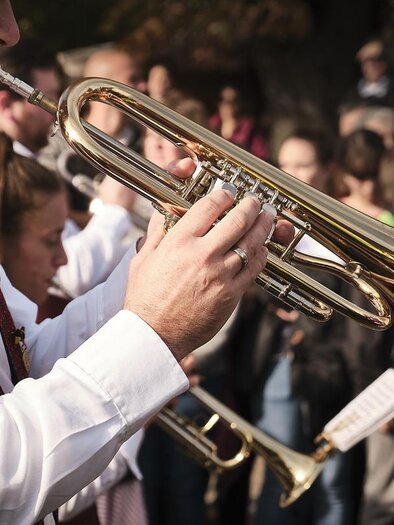Das Bild zeigt einen Mann in Tracht beim Spielen einer Trompete