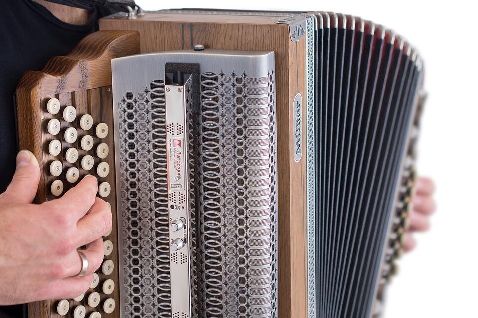 Ein Handspieler hält ein Akkordeon in den Händen. Das Instrument hat eine schöne Holzoberfläche und eine Vielzahl von Tasten. | © pixabay