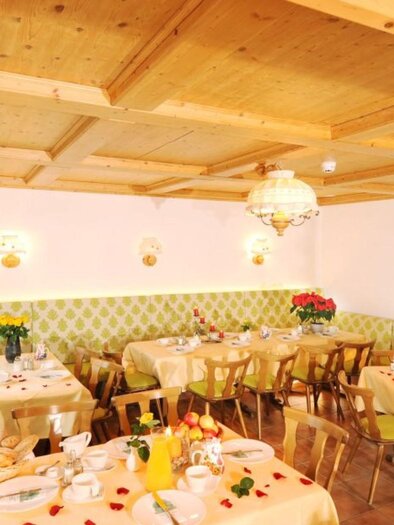 An inviting restaurant with bright tables and chairs. The walls are in soft colors, and the tables are decorated with fresh fruits. | © Hotel Seebacherhof